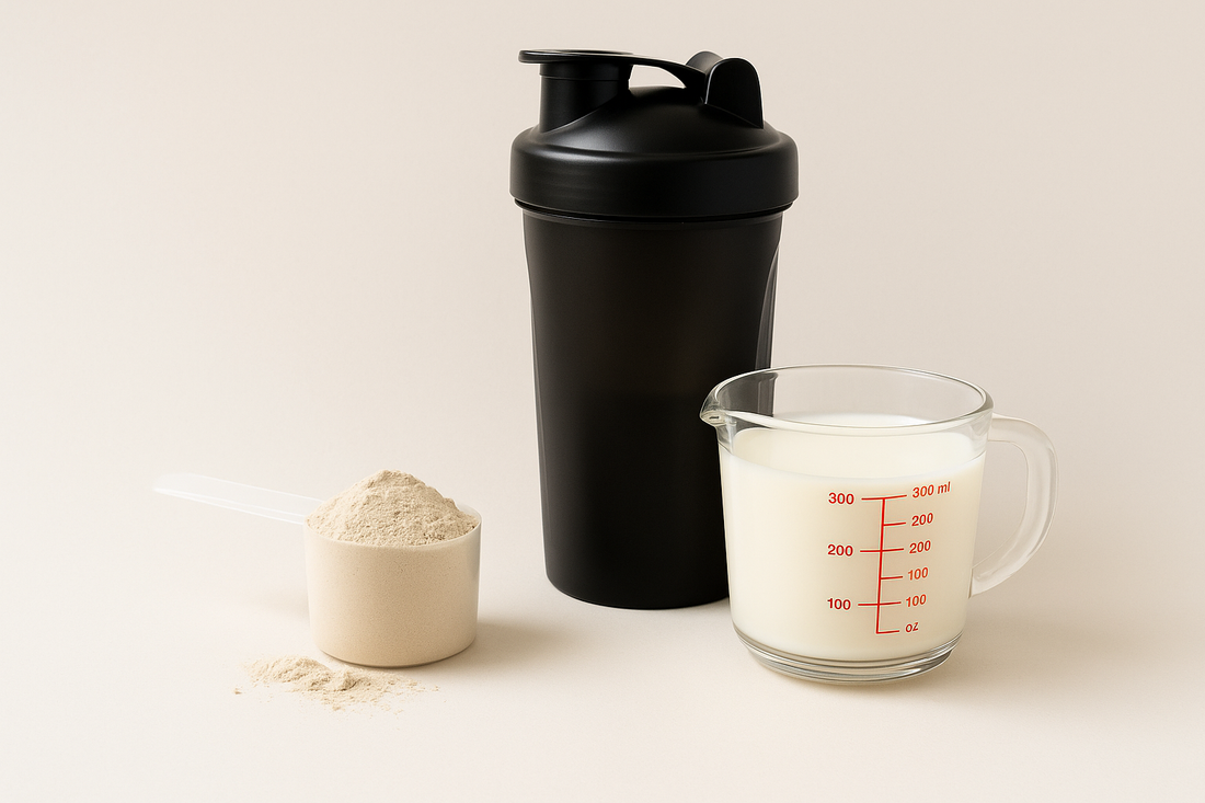 Scoop of protein powder, a shaker bottle, and a measuring cup of milk arranged on a clean, minimal background — representing protein supplement preparation.